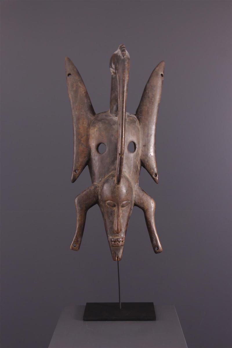 Masque en bois en forme d'animal se tenant à l'envers. Un visage se trouve entre les deux pattes avant. 