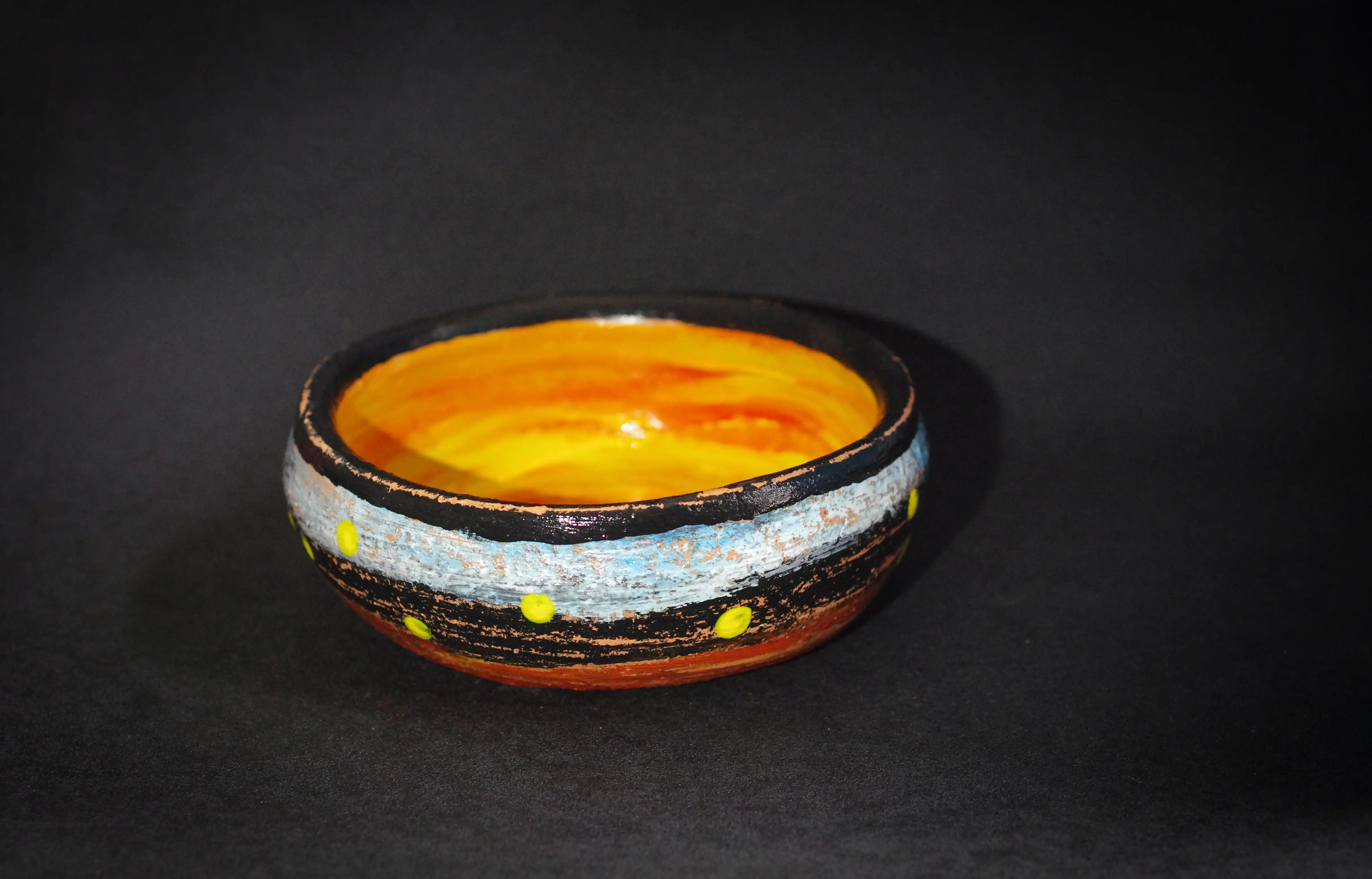 Cette poterie est similaire à CÉRAMIQUE N° : 008, mais plus petite et légèrement plus haute. L'intérieur est orange et jaune. Le bord est noir. L'extérieur est bleu clair, puis noir et orange (proche du rouge) vers la base. Le bord est parsemé de points jaunes irréguliers. C’est une œuvre d’art originale et de qualité. Une œuvre d'art soigneusement travaillée.  Une œuvre d'art créée avec un goût hautement artistique et un professionnalisme exceptionnels. Achat en toute sécurité. Un bon choix d’achat qui apportera une touche de détente à votre collection. 