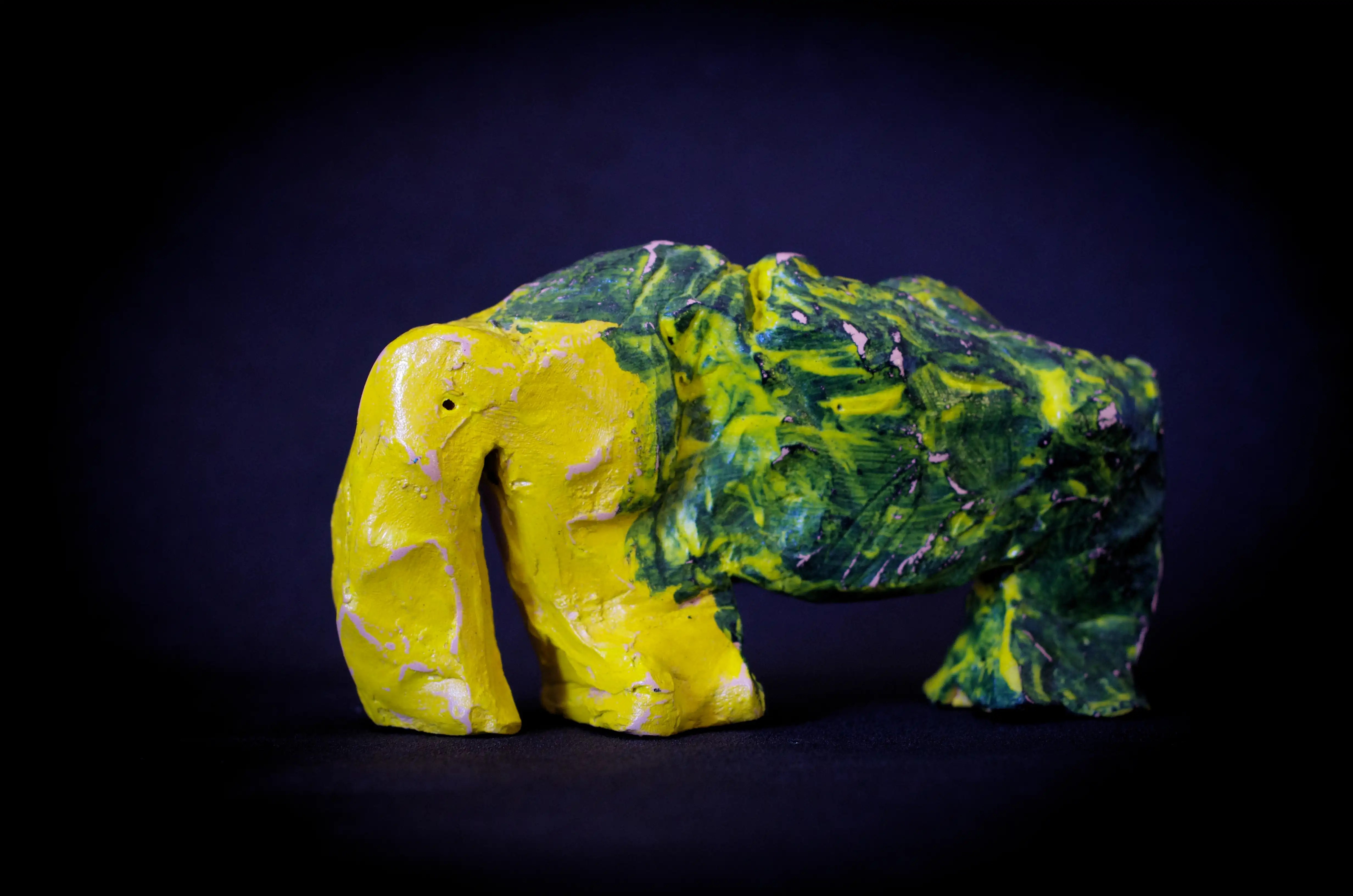 Il s'agit d'une sculpture animalière contemporaine, décorative et originale en terre cuite. Réalisée par modelage, cette sculpture en terre représente un éléphant dans un style libre, brut et unique. La surface est composée d'une peinture acrylique et d'un vernis appliqué après cuisson (« biscuit »). La tête et les pattes avant de cette pièce sont jaunes, le reste est vert foncé avec des mouchetures jaunes. Il s'agit d'une petite œuvre d'art créée à l'aide de différentes techniques de travail de l'argile et d'un bon exemple d'art céramique.